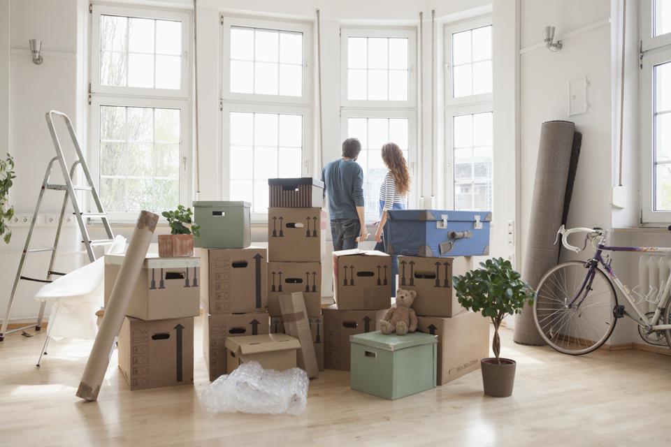 Couple with cardboard boxes in new apartment looking out of window