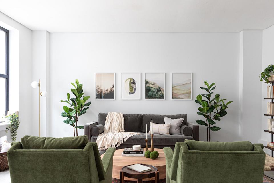 A living room at Common Frankford with green chairs and a grey sofa.