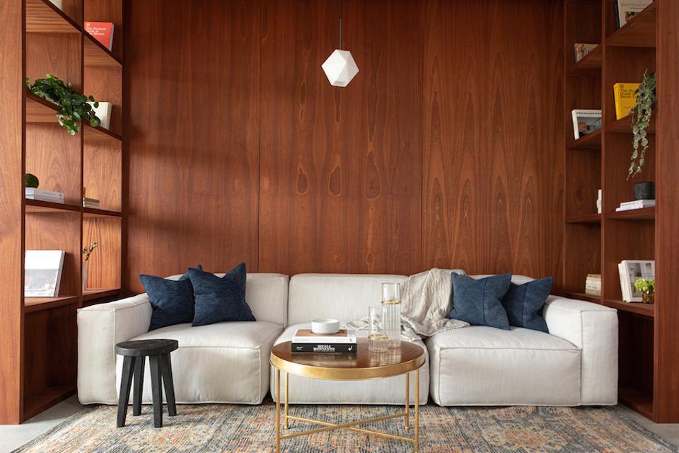 A white sofa against a wood wall and book shelves