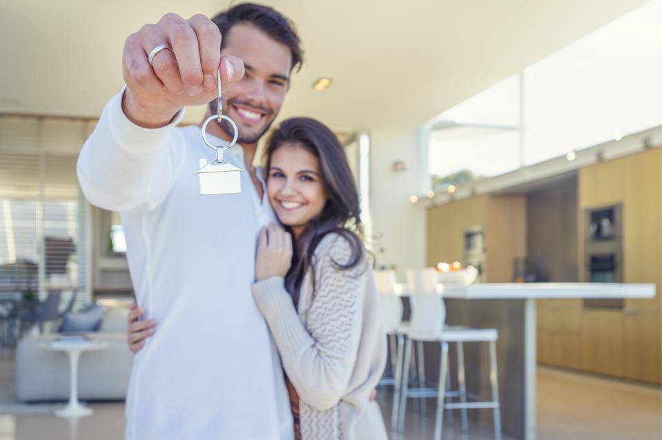 Couple holding a house key in their new home.